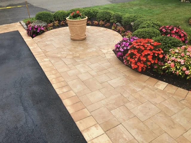Paver driveway apron bordered by flower beds