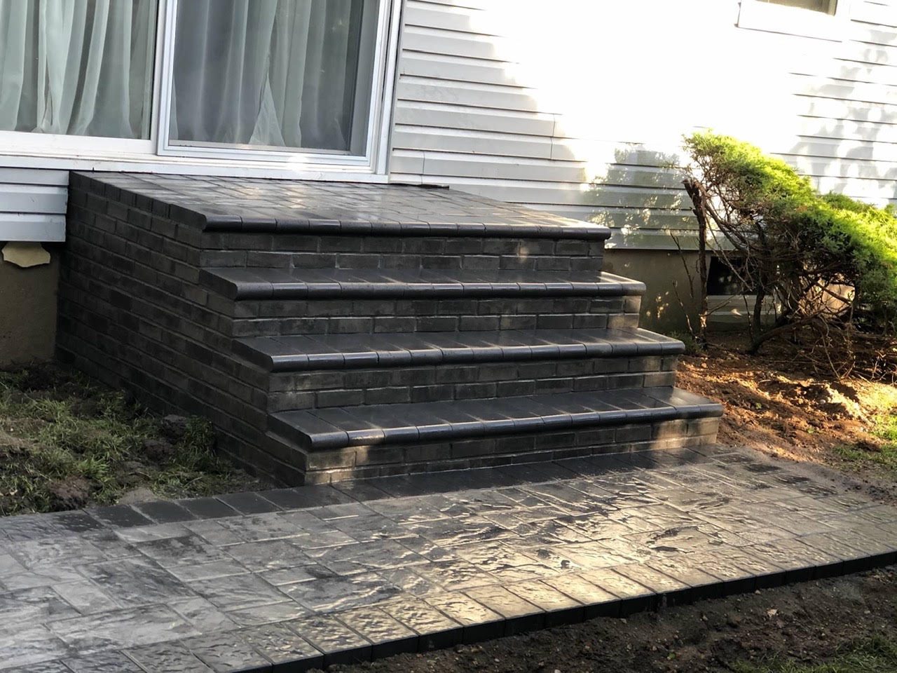 Charcoal brick stoop with four steps and stamped concrete walkway
