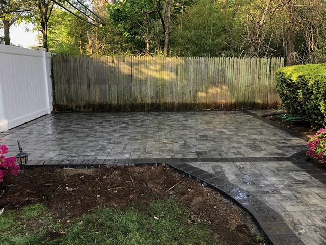 Rear paver patio installed along a fenced backyard