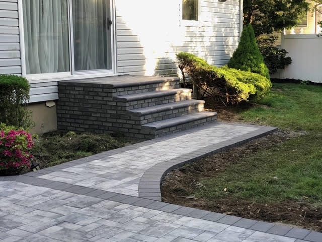 Gray paver walkway curving to brick steps and landing